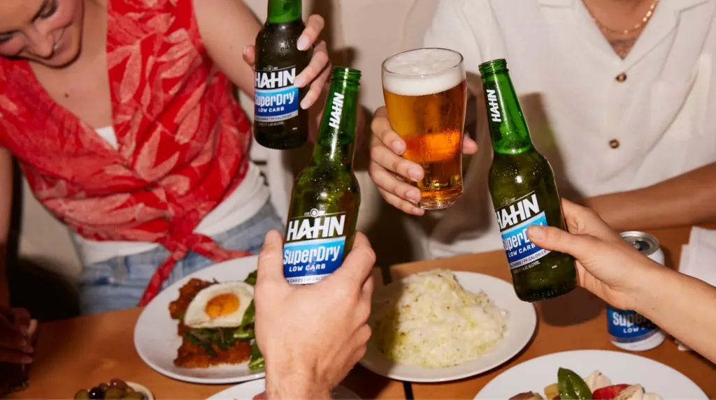 Four friends enjoying a meal and drinking Hahn SuperDry