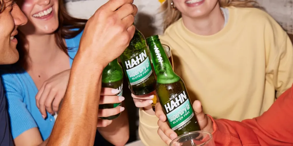 Four friends toasting bottles of Hahn SuperDry Gluten Free beer