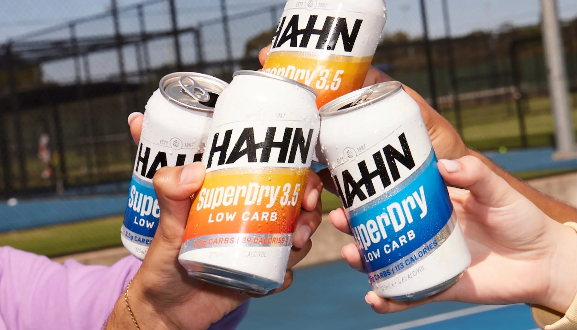Close-up photo of cans of Hahn SuperDry and SuperDry 3.5 being used for a toast