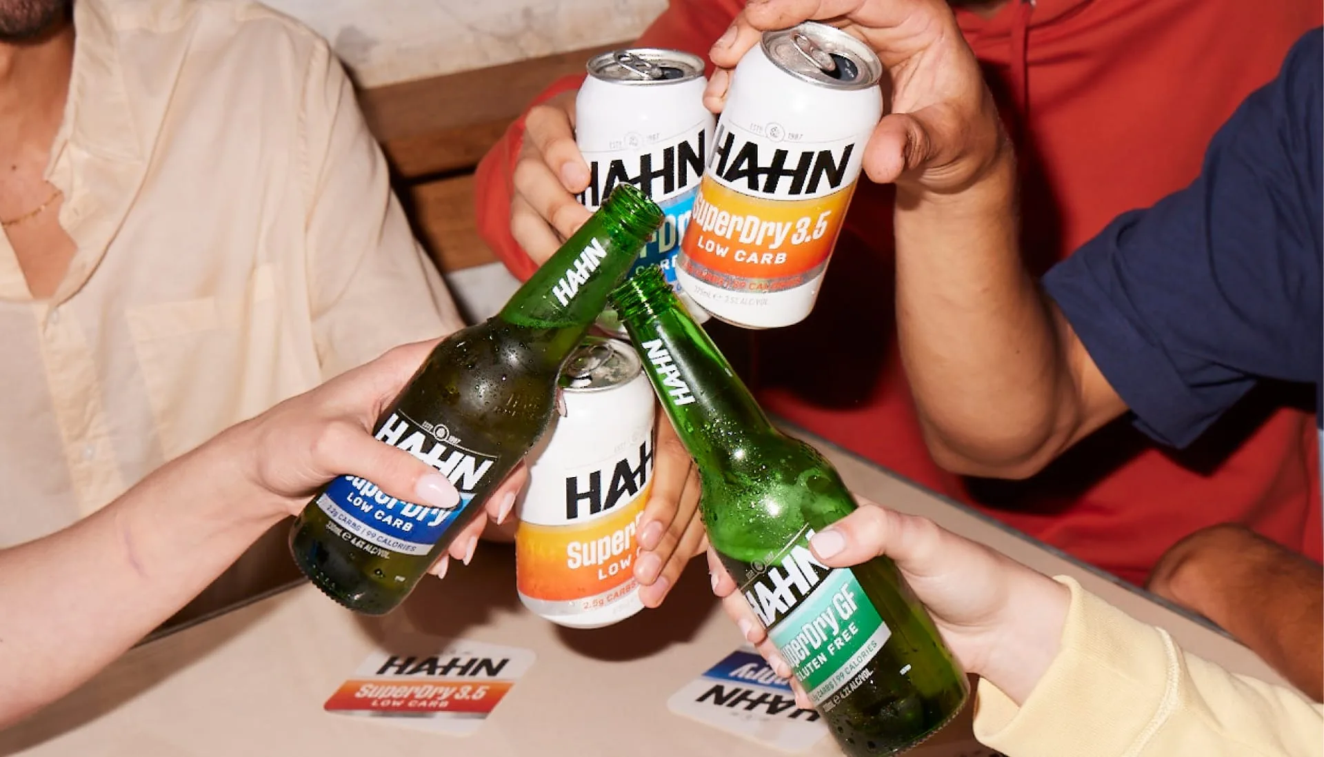 Friends toasting with bottles and cans of Hahn beer