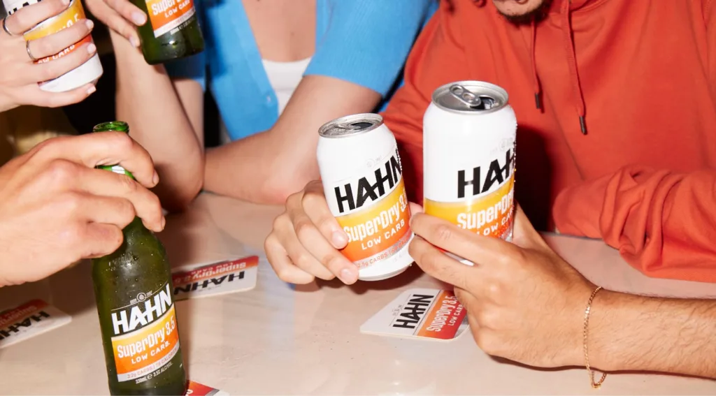 Close-up photo of five friends at a table drinking Hahn SuperDry 3.5 cans and bottles